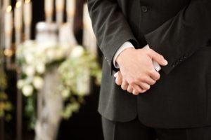 Man solemnly holding hands at funeral.