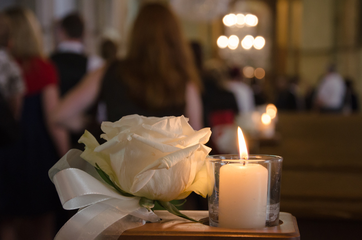 Candle and white rose at ceremony.